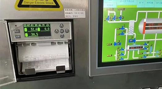 Chart recorder with paper chart roll Chart recorder with a paper chart roll installed on a panel beside a process HMI screen
